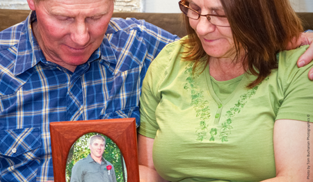 Mom and Dad hold framed photo of son