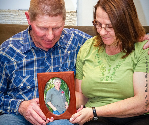 Dad and Mom hold framed photo of son
