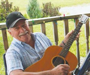 Man holding guitar while sitting on porch