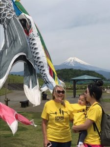 Two women, one holding a toddler, stand with Mount Fuji in the background.