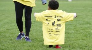 Young boy shows off the back of his oversized t-shirt with names of event sponsors