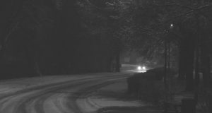 black and white photo of car headlights on snowy road