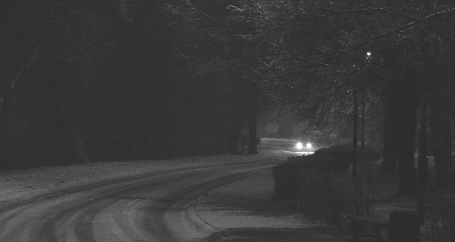 black and white photo of car headlights on snowy road