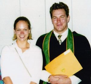 Young woman and man in graduation clothing smile for camera