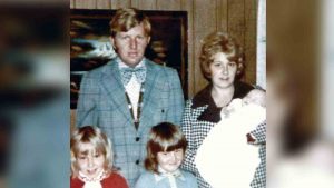 Man in suit and bowtie stands with woman and three young girls