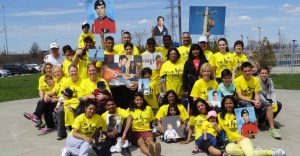 Large group of people in yellow T-shirts holding signs with photos of a young man