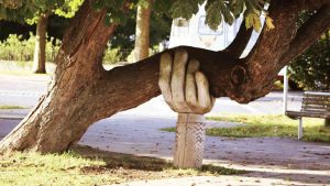 a carved hand supports a leaning tree