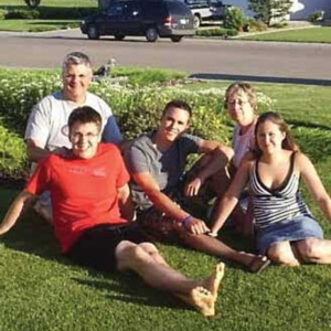 Man, woman, two teenage boys and a teenage girl sitting on a lawn