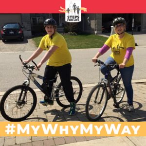 Boy and woman wearing yellow T-shirts and helmets sit on bikes