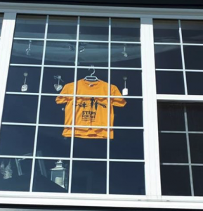 A lone yellow T-shirt hangs in a window