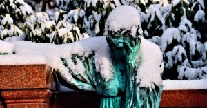 Statue of grieving figure covered with snow