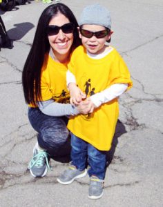 woman in sunglasses crouched down posing with a small child in sunglasses