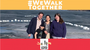 A family stands in front of an open body of water. Hashtag reading #WeWalkTogether is above them and Steps for Life logo underneath.