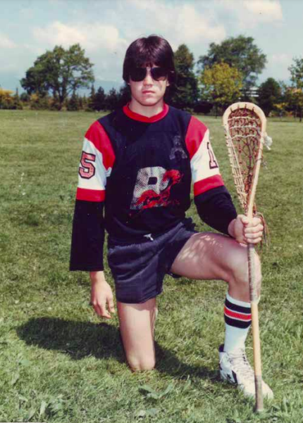 Young man kneeling and holding a lacrosse stick