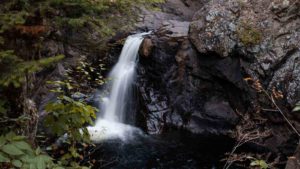 waterfall cascades over rocks into water below