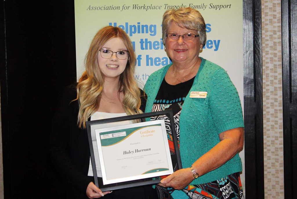 Older woman with short hair and glasses stands with young woman with long blonde hair and glasses holding certificate.