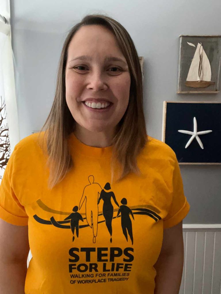Young woman smiles brightly while wearing a yellow Steps for Life T-shirt
