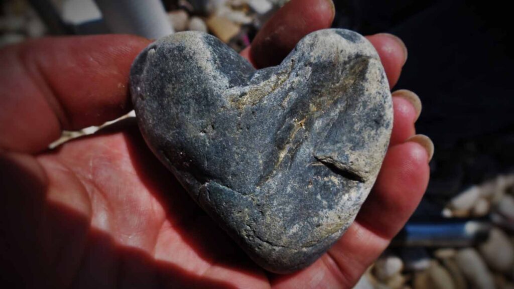 blue heart shaped rock held in an open palm