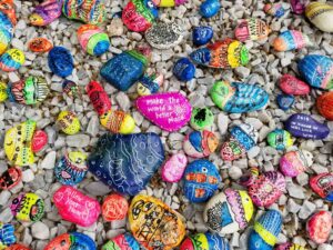 brightly painted rocks with sayings "Follow your heart" and "make the world a better place" painted on them.
