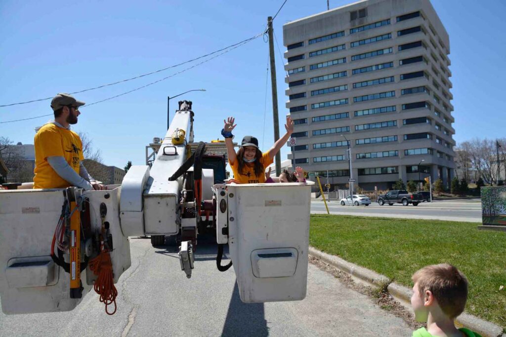 A young girl raises her hands as she gets to ride in the bucket truck