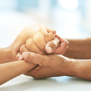 Two pairs of hands grasped across a table