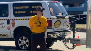 A man in a Steps for Life T-shirts stands in front of a Trinity Safety van.